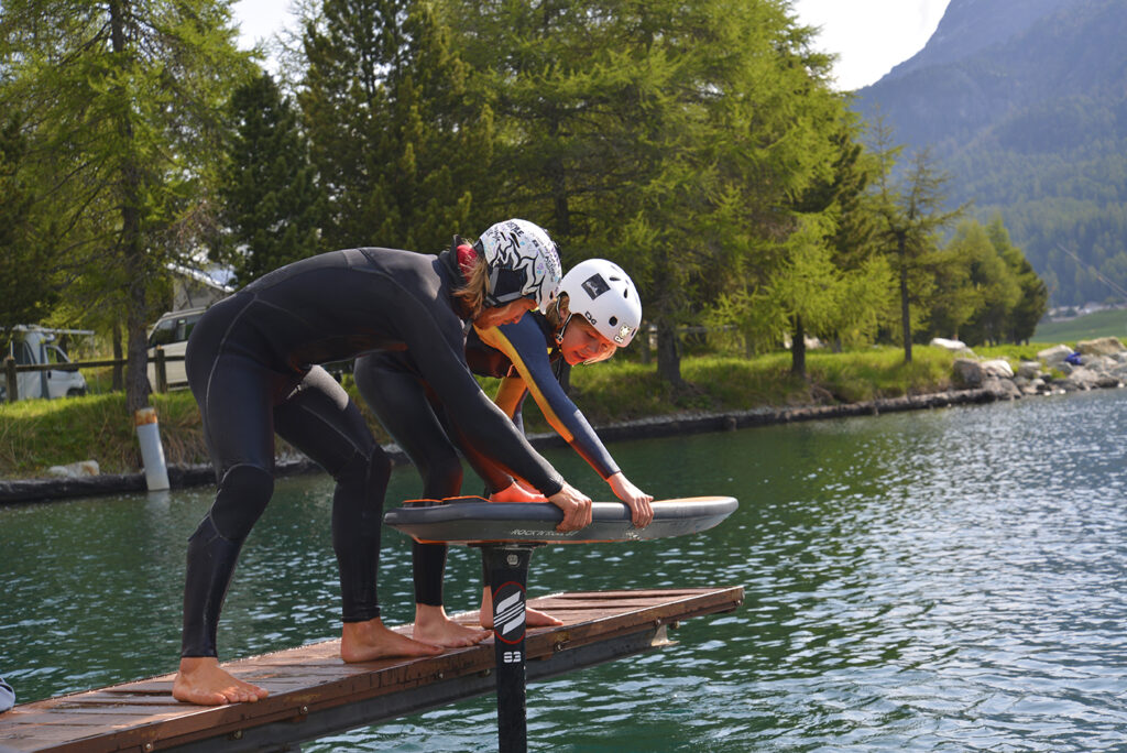 two people about to be pump foiling on a lake 