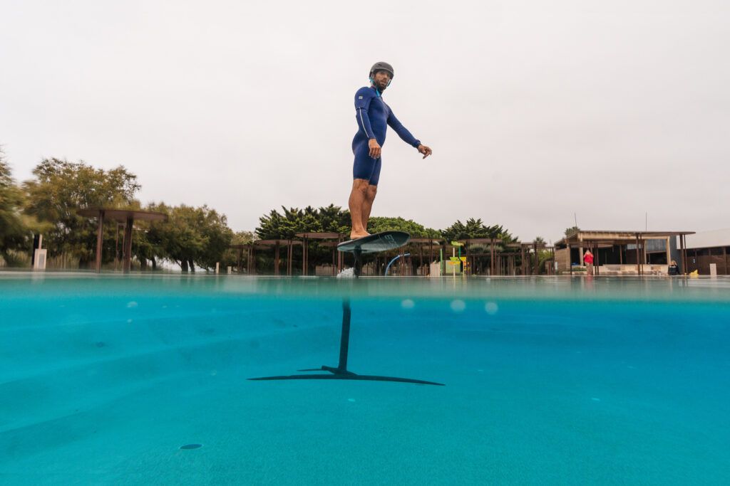 man hovering above swimming pool on a wing foil