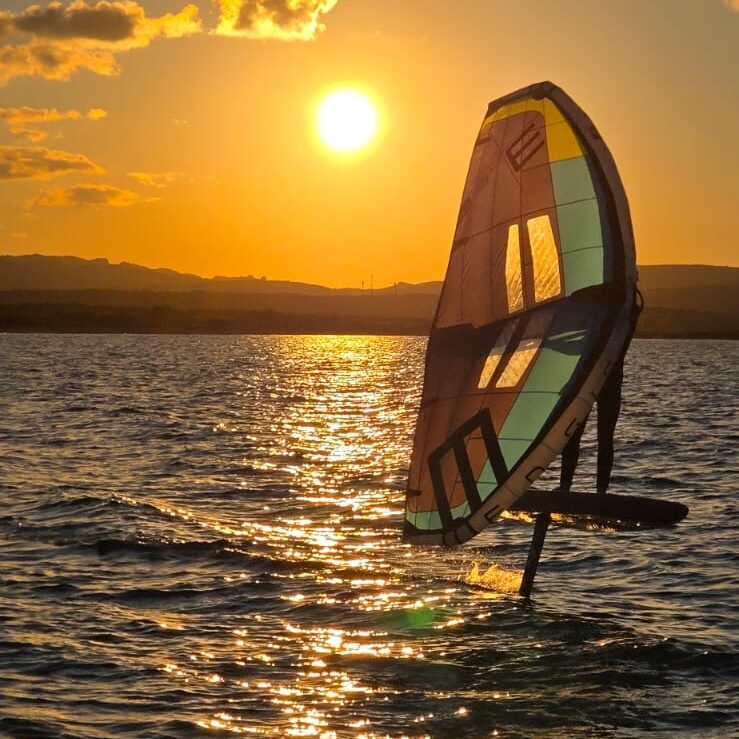 person with wing foil on lake at sunset